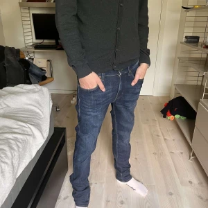 Mörkblå Tiger of Sweden jeans 30/32 - Snygga mörkblå jeans från Tiger of Sweden, modell Leon. En slimfit passform. Jeansen är i bomull och har stilrena detaljer med orange sömmar. Perfekta för dig som gillar en clean och tidlös look.
