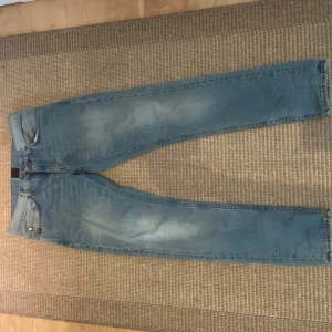 Ljusblå tiger of sweden jeans - Säljer ett par ljusblå jeansbyxor med klassisk femficksdesign och raka ben. Jeansen har en snygg tvättad look och kontrastsömmar på back fickorna. De sitter ganska tajt och är väldigt stilig skinny jeans. Storlek 31x32 men sitter mer som 30x32. Stil: pistolero