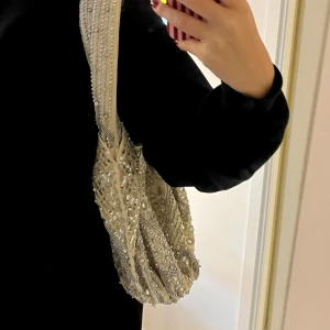 Beige axelväska med paljetter och pärlor - Zara - Superfin beige axelväska med massor av paljetter, pärlor och glittriga detaljer. Använd fåtal gånger, som ny.