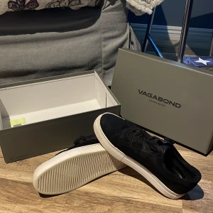 Svarta Vagabond Paul 2.0 sneakers - Svarta sneakers från Vagabond, modell Paul 2.0, med ovandel i mocka och klassisk vit platt sula. Skorna har rund tå och snörning framtill för en clean och stilren look. Ny pris runt 1000kr till 2000kr men jag säljer dem för 300. Pris kan diskuteras 