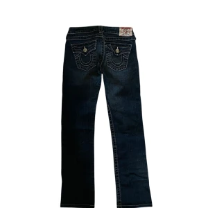 True Religion Billy low waist jeans - Snygga mörkblå jeans från True Religion. Jeansen är low waist och har lite av en bootcut passform. Plagget är i princip orört och har inga större defekter eller fläckar.Skicka meddelande vid fråga📢❓.                                                                                 Mått: Midja tvärs över 35 cm, innerbens längd 71 cm, ben öppning 18 cm. 