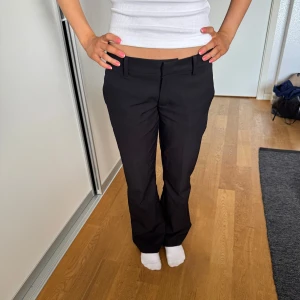 Svarta kostymbyxor med bootcut - Snygga svarta kostymbyxor i bootcut med låg midja. Byxorna har hällor för bälte och klassisk rak passform. Perfekta för en clean och stilren look. ☺️Byxorna är i bra skick, med en liten defekt ( litet hål i fickan som knappt märks av )😀Jag säljer de pågrund av att jag har ett par likadana. Nypriset är 500kr från BikBok                  