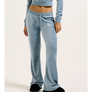 Blå velour mjukisbyxor och tröja från Juicy Couture - Tröja och byxor, ett sett från juicy couture. Fickor bak, snöra framtill. Mysigt material. Nypris: 3000 sammanlagt. (1500 tröja) (1400 byxor)                            Går att köpa separat också