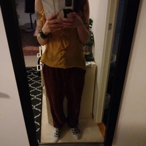 Gul volang-linnetopp med smala axelband - Säljer en snygg gul linnetopp med smala axelband och volangdetaljer framtill. Toppen har en lös passform och är tillverkad i ett lätt, flowy material som känns luftigt. Perfekt för dig som gillar en chill och trendig stil.