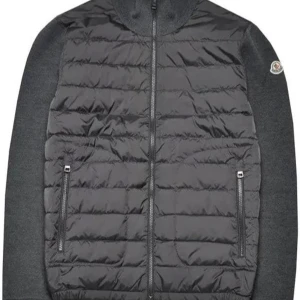 Grå cardigan jacka från Moncler - Snygg grå cardigan jacka från Moncler enligt bild med quiltad front och stickade ärmar. Jackan har dragkedja framtill, två fickor med dragkedja och Moncler-logga på ärmen. Perfekt för dig som vill ha en stilren och sportig look.
