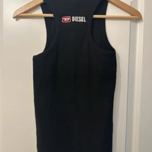 Svart ribbad topp från Diesel - ascool ribbad topp från Diesel med logga baktill. loggan har lossnat pyttelit bak, vilket säkert går att fixa lätt, annars i fint skick. 