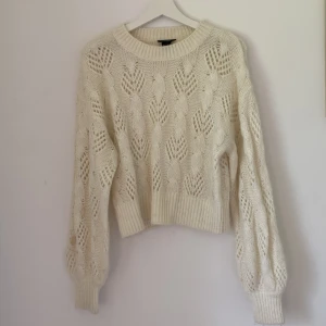 Vit stickad tröja från Lindex - Superfin vit stickad tröja från Lindex i storlek S. Tröjan har ett snyggt flätmönster med hålstickade detaljer och breda muddar vid ärmslut och nederkant. Perfekt för lager-på-lager och ger en mysig vibe till din outfit.