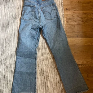 Levi's Ribcage Crop Flare jeans ljusblå strl 23 - Säljer ett par Levi's Ribcage Crop Flare jeans i ljusblå denim. Hög midja, croppad längd och utsvängda ben. Klassisk femficksmodell med Levi's logga på bakfickan. Perfekta för dig som gillar retrovibbar och snygg passform. Storlek 23, men är stora i storlek så passar 24!