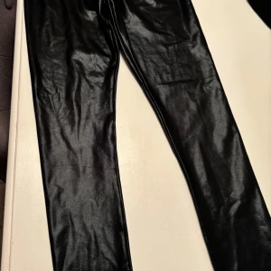 Svarta glansiga leggings från Name It - Säljer ett par svarta glansiga leggings från Name It i storlek 146. De har en tight passform och resår i midjan. Perfekta för dig som vill ha en cool och trendig look med lite extra edge. Skriv vid frågor!💗