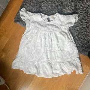 Vit volang blus från Gina Young  - Supersöt vit blus från Gina Tricot med volangkant nertill och korta ärmar. Blusen har en luftig passform och är gjord i ett lätt material, perfekt för varma dagar. Söt detalj med liten knapp i nacken. Den är ifrån Gina Young o skriv om ni vill ha någon bild eller har någon fråga💞Jag säljer den då den är för stor och den kommer aldrig till användning o tycker ändå att den har ganska bra sick!!💞
