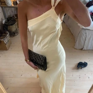 Ljusgul långklänning med knyt i ryggen - Superfin ljusgul långklänning med oneshoulder och öppen rygg från by stina💗. Klänningen har ett snyggt knytband i ryggen och är figurnära med slät, elegant look. Perfekt för sommarens speciella tillfällen och ger en riktigt chic vibe. Använd 1 gång