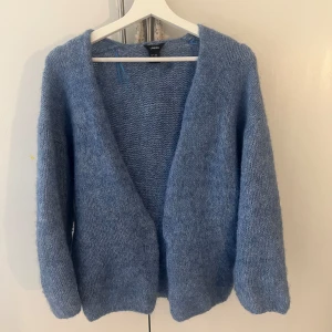 Blå stickad kofta från Lindex - Mysig blå stickad kofta från Lindex med lång ärm och öppen front. Perfekt för lager-på-lager och chill dagar. Koftan har en mjuk känsla och en enkel, avslappnad passform.