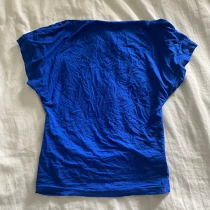  topp med öppen rygg  - Säljer en blå topp från SHEIN i storlek S/36. Toppen har en öppen rygg och är tillverkad i mjukt och stretchigt material. Jag har använt den 1 gången, och den har legat i min garderob sen dess typ (tvättad också), men det är därför den är skrynklig.
