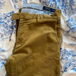 Manchesterbyxor - Ralph Lauren - Snygga olivgröna manchesterbyxor från Polo Ralph Lauren. Byxorna har raka ben, bälteshällor och klassiska fickor både fram och bak. Tillverkade i mjuk manchester som ger en retro och chill vibe. Perfekta för dig som gillar stilrena och bekväma plagg.