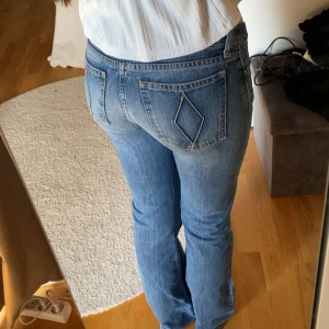Blå Replay bootcut jeans - Snygga blå jeans från Replay med bootcut passform och låg midja. Klassisk femficksmodell med unika diamantformade sömmar på bakfickorna. Jeansen är i mjukt denimtyg och har en lätt tvättad look som ger en cool vibe. Midjemått 37, Inrebenslängd 81