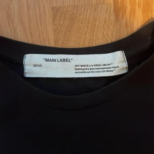 Svart Off-White t-shirt - Svart t-shirt från Off-White med vit text '99' och 'IMPRESSIONISM' tryckt på framsidan. Design av Virgil Abloh. Perfekt för dig som gillar exklusiva och trendiga plagg. Listpris:Ca 4000kr