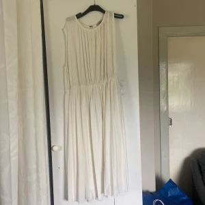 Vit plisserad långklänning H&M XL - Säljer en vit långklänning från H&M i storlek XL. Klänningen är ärmlös, har plisserat tyg och rund halsringning. Den har ett lätt och flowy fall, perfekt för sommarens alla tillfällen. Enkel och stilren design som känns både fräsch och modern.