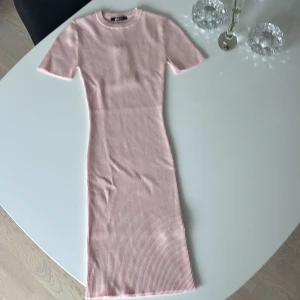Ribbad rosa klänning - Supersöt ribbad kortklänning i rosa från gina tricot. Klänningen har korta ärmar, rund halsringning och en figurnära passform. Materialet är mjukt och stretchigt för extra komfort. Aldrig använd därav är prislappen kvar, dock utan priset kvar då jag fick den i present.