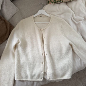 Vit kofta från Gina Tricot - Mysig vit och stilren kofta från Gina Tricot med rund halsringning och knäppning framtill. Passar även M