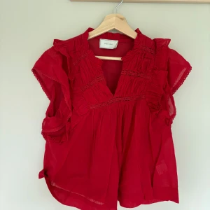  blus med volang från Neo Noir - Säljer en röd blus från Neo Noir med volangdetaljer och v-ringning. 