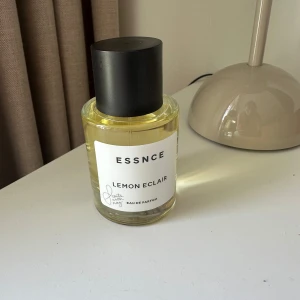 ESSNCE Lemon Eclair Eau de Parfum - Fräsch parfym med doft av citron, Lemon Eclair från ESSNCE. Flaskan är cylindrisk i genomskinligt glas med svart rund kork och vit etikett. Perfekt för dig som gillar fruktiga och söta dofter.