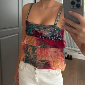 Färgglad mönstrad linnetopp från Zara - Säljer en färgglad och luftig linnetopp från Zara med volangdetaljer. Toppen har smala axelband med glittriga detaljer och ett abstrakt mönster i rosa, grön, gul och röd. Perfekt för varma dagar och somriga outfits.