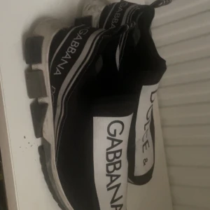 Svarta sneakers från Dolce & Gabbana - Snygga äkta sneakers från Dolce & Gabbana i storlek 43. Svarta med vit logga, stretchigt tyg och chunky sula. Använda men i bra skick – lite smuts på sulan men inget som stör. Väldigt bekväma och sticker ut i mängden. Säljer pga att jag inte använder dem längre.