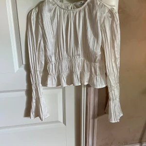 Gullig blus från H&M - En gullig långärmad blus från H&M med veckade detaljer på ärmarna och runt midjan. Knäpps med en knapp i nacken. Kolla min profil för fler kläder!