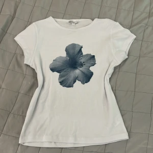 Vit t-shirt med blommotiv från Subdued - MEDDELA INNAN KÖP TACK, säljer en vit t-shirt från Subdued med en stor, gråblå blomma tryckt på framsidan. T-shirten har rund halsringning och korta ärmar, säljer eftersom att jag tycker att den inte passar på mig. T-shirten är aldrig använd, bara när jag har testat den och skulle se hur den såg ut på❤️ 