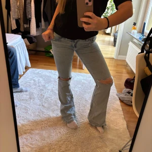 Ljusblå bootcut jeans med hål på knäna - Trendiga jeans från Nelly, sparsamt använda men de är för långa för mig så det har bildats hål längst ner, syns inte jätte mycket när man har skor osv, går ju såklart också att klippa av(: