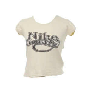 Vintage babytee från Nike - Gul vintage babytee från från Nike.  Svart ’Nike Country' tryck på framsidan. Croppad och korta ärmar. Supersnygg men tyvärr lite urtvättad/nopprig, därav lågt pris 🔥
