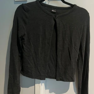 Mörkgrå kofta  - Säljer en grå kofta från Gina Tricot. Tröjan har långa ärmar, rund halsringning och en enkel knapp framtill. Skicka gärna till mig vid vidare frågor😊🫶🩷