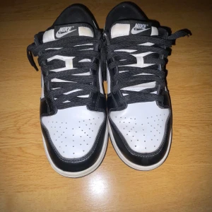 Nike Dunk Low Panda - Säljer ett par klassiska Nike Dunk Low Panda sneakers i svart och vitt. Skorna har svart snörning, rund tå och platt sula. Perfekta för dig som gillar stilrena och tidlösa sneakers med ikonisk design.