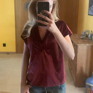 Vinröd sammetsblus med v-ringning - Vinröd blus i mjuk sammet med v-ringad hals och korta ärmar. Skön passform och utan synliga detaljer. Perfekt för dig som gillar en stilren och bekväm topp. Jättefin i solljus haha😍