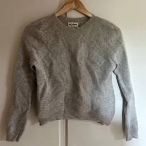 Ljusgrå stickad tröja från Soft Goat - Mysig ljusgrå stickad tröja från Soft Goat i 100% kashmir. Använd en del men i fint skick och väl omhändertagen utöver två små hål på ärmen (se sista bilden), därav priset, men det är inget som märks och går att fixa om man vill. Nypris ca 2800kr