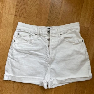 Vita jeansshorts från 157 - Helt nya och oanvända! Snygga vita jeansshorts med hög midja och klassisk femficksdesign. Shortsen har uppvikta benslut och silverfärgade knappar. Perfekta för varma dagar och enkla att matcha med olika toppar. Supersnygga!