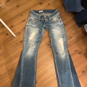 Blå bootcut jeans med slitningar - Säljer ett par blå utsydda bootcut jeans med slitningar framtill. De är väldigt lågmidjade. Midjemått 35 cm tvärs över midjan och innerbenslängd 78 cm. Kontakta mig privat vid frågor eller liknande💕