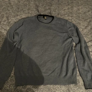 Blå kashmirtröja från Blu Cashmere - Säljer en stilren blå kashmirtröja från Blu Cashmere. Tröjan har rund halsringning, långa ärmar och ribbade muddar vid ärmslut och nederkant. Perfekt för dig som gillar klassisk och mjuk stil. Den har nått litet hål som knappast syns. Annars är den i bra skick!