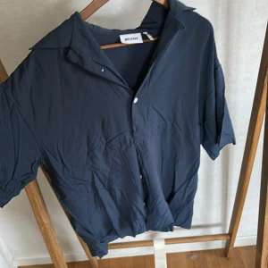 Mörkblå kortärmad skjorta från Weekday - Säljer en mörkblå skjorta från Weekday med korta ärmar.