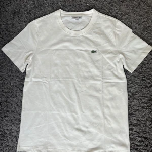 Vit t-shirt från Lacoste - Storlek M vit t-shirt från Lacoste. gröna krokodilloggan broderad på på bröstet. Jätte bra material och kvalite. Nästan helt oanvänd och helt ren. Perfekt till sommaren. PRISET KAN DISKUTERAS.
