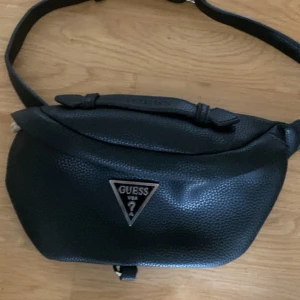 Guess axelväska svart  - En guess axelväska som jag fick i present men som jag ej behöver. Nypris ca 1500 kr. Mitt pris 749 kr! Perfekt skick endast använd 2 gånger.   Den är äkta och ritkigt smidig då man kan justera l än längden så den passar alla! Pris går och diskutera så hör av er vid frågor!! 
