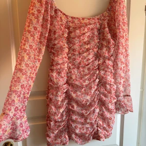 Blommig rosa långärmad klänning med volang - Supersöt kortklänning. Något liten i storlek.