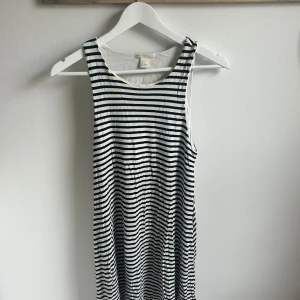 Randig ärmlös klänning från H&M BASIC - Säljer en svartvit ärmlös klänning från H&M BASIC i storlek S. Klänningen har smala axelband och ett klassiskt randigt mönster. Perfekt för varma dagar och enkel att styla med sneakers eller sandaler.