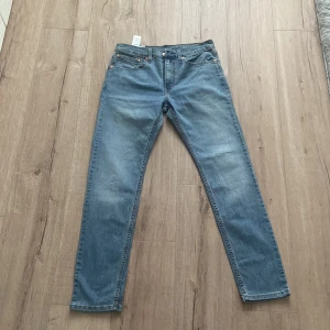 Levi's 512 blå jeans W31 L32 - Säljer ett par klassiska blå Levi's 512 jeans med normal passform och raka ben. Jeansen har fem fickor, dragkedja och knapp i midjan samt den ikoniska Levi's-lappen bak. Perfekta till vardags och passar till det mesta.