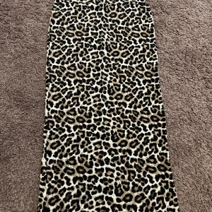 Leopardmönstrad långkjol - Säljer en snygg långkjol från Lindex med leopardmönster i beige, svart och brunt. Kjolen har en rak passform och dragkedja i sidan. Perfekt för dig som vill sticka ut med ett djurmönstrat plagg.