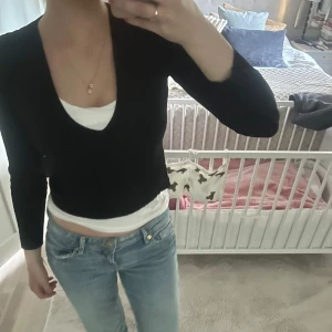 Svart croppad v-ringad tröja - Svart croppad tröja med v-ringning och långa ärmar. Snygg och enkel modell som passar perfekt till jeans eller kjol. Tröjan har en figurnära passform och är lätt att matcha med olika stilar.