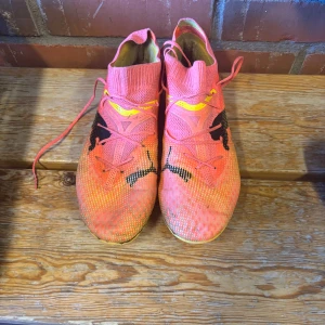 Puma fotbollsskor  - Säljer ett par fotbollsskor från Puma i en snygg orange färg med gula. Storlek 41 använda rn halv gräs säsong. Medium skick men jätte bekväma.