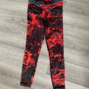 Bettet Bodies tights - Säljer ett par svarta tights med rött abstrakt mönster från Better Bodies. De har en tight passform och är perfekta för träning eller gym. Materialet är stretchigt och bekvämt.