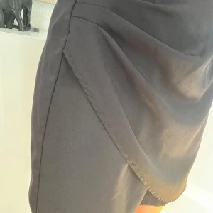 Svart omlottkjol från SHEIN - Säljer en svart omlottkjol från SHEIN i storlek S. Kjolen har en snygg omlottdesign med markerad kant och är perfekt för dig som gillar stilrena plagg. Enkel att matcha med olika toppar och skor.