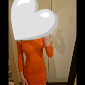 Orange tight klänning - Säljer en snygg orange klänning med tight passform och medellånga ärmar. Klänningen är kort och har en enkel, stilren design som framhäver figuren. Perfekt för dig som vill sticka ut med färg!